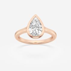 a rose gold ring with a pear shaped diamond in the center, on a white background