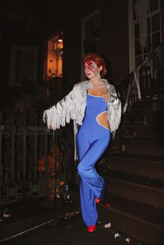 a woman with red hair wearing blue pants and a white jacket