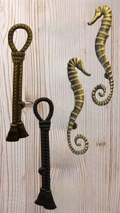 three seahorses are hanging on a wood paneled wall with an iron hook