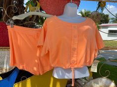 "Women's 1980's Neon Orange 2 Piece Short Set by Borderline Cot'n Gear Canada Drawstring waist & crop top hemline 100% cotton 1-1/2 inch waistband on shorts with 1 inch hem & 24 inch leg circumference Measurements in inches: Top 38\" bust 38\" at the hemline 28\" neck 5\" underarm to hemline 3-1/2\" underarm to sleeve hemline 6-1/2\" shoulder to sleeve hemline 19\" shoulder to shoulder from the back 13\" neck to hemline from the back Shorts 36\" waist 40\" hips 2-1/2\"inseam 11\" side wa 2 Piece Short Set, Orange Outfit, Orange Shorts, Short Set, Neon Orange, Short Sets, Drawstring Waist, Off Shoulder Blouse, Open Shoulder Tops