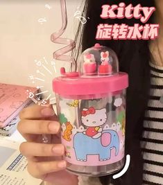 a woman holding up a hello kitty cup