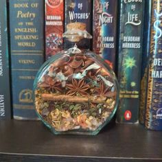 a glass bottle filled with lots of different types of spices on top of a book shelf