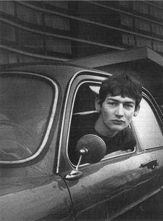 an old photo of a young man sitting in a car looking out the window with his head sticking out