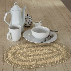 a placemat, coffee cup and saucer on a table with teapots