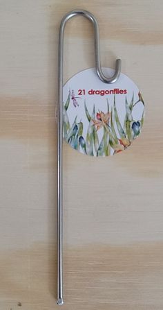 a metal hook with a sticker on it that says 21 dragonflies in the grass