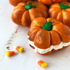 several small pumpkins with green leaves and candy corn on the ground next to them