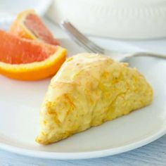 a piece of bread on a plate next to an orange