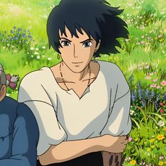 an older man and young woman sitting on the grass in front of some wildflowers