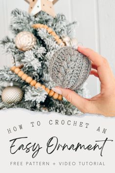 a hand holding a crochet ornament in front of a christmas tree