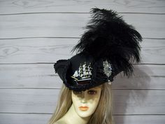 "Beautiful black woolen blend pirate/tricorn hat with black ruffled satin trim and black braid trim on top, black flared ostrich feathers, black cocarde with jewel and a wooden ship! This hat is about 22 1/2\" for the inside circumference and does have a built in hat sizer but if you feel you need a peel and stick hat sizer then let me know and I can include one in your package at no charge. I ship Priority mail. I ship many times a week. If you need your item quicker let me know your zip code a Pirate Hat Feather, Adjustable Brimmed Pirate Hat, Black Adjustable Pirate Hat, Victorian Pirate, Pirate Hat With Feathers, Pirate-style Brimmed Hat For Costume Party, Black Pirate, Tricorn Hat, Pirate Hat