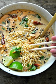 someone holding chopsticks over a bowl of noodles