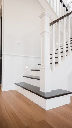 an empty room with stairs and hard wood flooring on the side of the wall