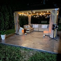 an outdoor living area lit up at night with string lights on the roof and couches