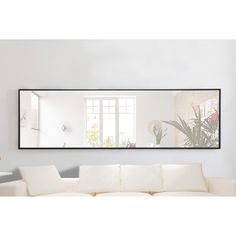 a white couch sitting under a large mirror in a living room