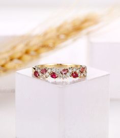 a diamond and ruby ring sitting on top of a white box with wheat stalks in the background