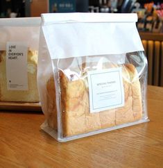 two bags of bread sitting on top of a wooden table