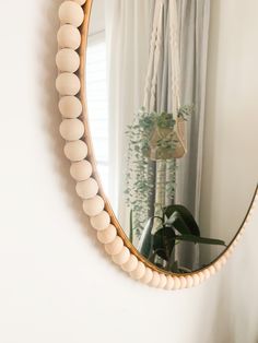 a round mirror hanging on the wall next to a potted plant