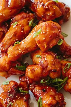 chicken wings with sesame seeds and garnishes on a white plate