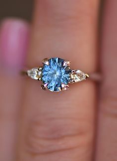 a woman's hand holding a blue and white ring with two diamonds on it