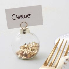 a table setting with silverware and a glass ornament filled with gold stars