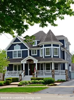 a large blue house with white trim on the front porch and two car garages