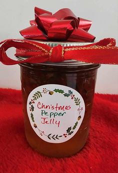 a glass jar filled with jelly sitting on top of a red blanket next to a bow