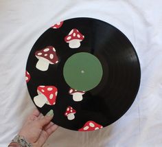 a person holding up a black record with mushrooms on it and green disc in the middle