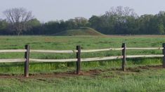 a wooden fence in front of a grassy field