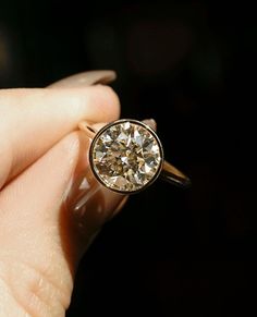 a woman's hand holding a ring with a diamond in it and the middle one is yellow gold