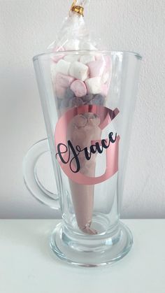 a clear glass cup with pink and white candies in it that says grace on the side