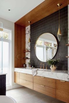 a bathroom with marble counter tops and wooden cabinets, along with a round mirror on the wall