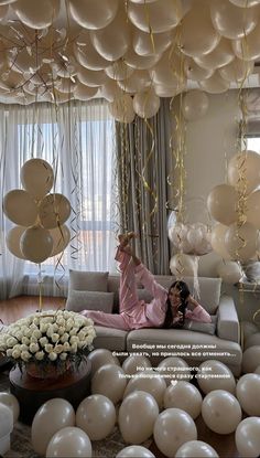 a woman sitting on a couch surrounded by balloons