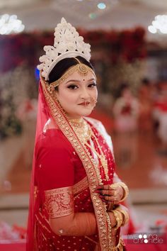 a woman wearing a red and gold bridal outfit with a tiara on her head