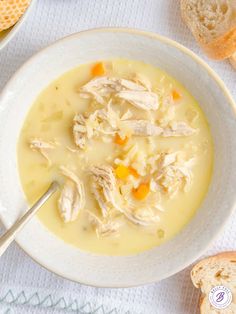 a bowl of chicken and dumpling soup on a white tablecloth next to bread