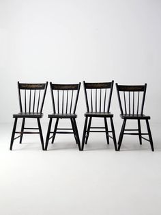 three wooden chairs sitting side by side in front of a white wall with no one on it