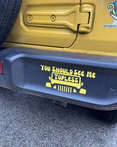 the back end of a yellow vehicle with stickers on it's bumpers