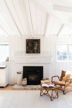 a living room filled with furniture and a fire place next to a kitchen area covered in white walls