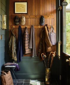 a coat rack with umbrellas and hats hanging from it's sides next to a window