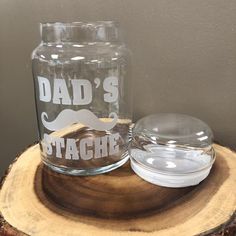 a glass jar with the words dad's tache on it next to a lid