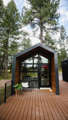 a wooden deck with a chair and table on it next to a large pine tree