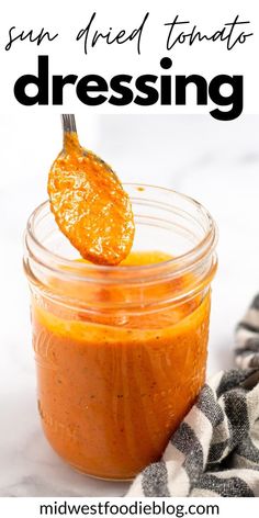 a jar filled with orange sauce on top of a white counter next to a black and white towel