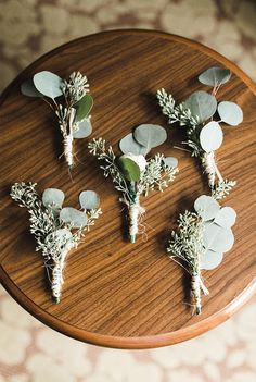 flowers and greenery are arranged on a wooden table in order to be used as centerpieces