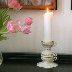 a lit candle is sitting on a table next to some tulips in a vase