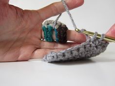 someone is crocheting something with yarn on their fingers and holding it in the other hand