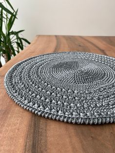 a close up of a rug on a wooden table with a plant in the background