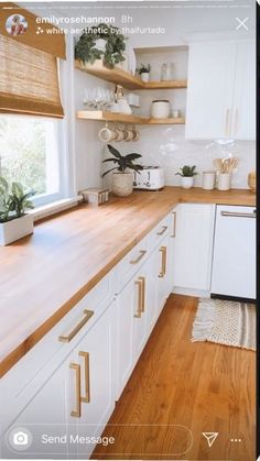 a kitchen with white cabinets and wooden counter tops, plants on the window sill