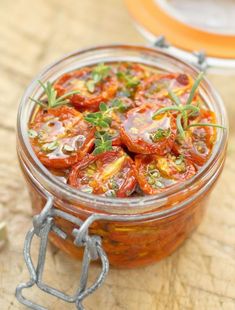 a glass jar filled with tomatoes on top of a wooden table