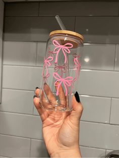 a person holding up a cup with pink bows on the lid and straw in their hand