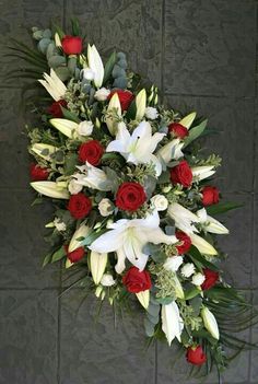 a bouquet of white and red flowers with greenery in the middle on a tile floor