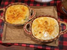 two casserole dishes sitting on top of a wooden cutting board